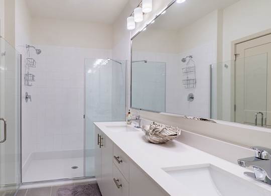 A bathroom with a white sink, mirror, and shower.