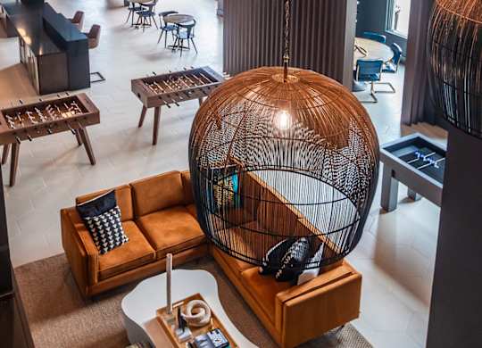 a room with a large bird cage hanging from the ceiling and a lobby with furniture