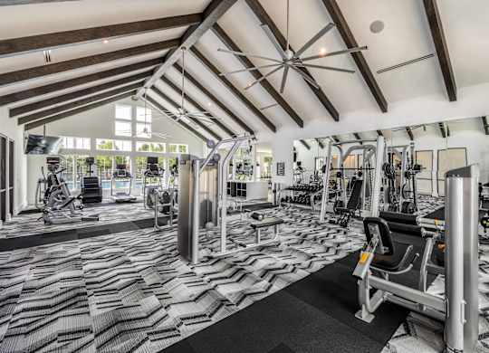 A gym with a variety of equipment including treadmills, weights, and exercise machines.
