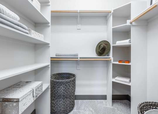 A small, white, and clean room with a bed, a chair, and a trash can.