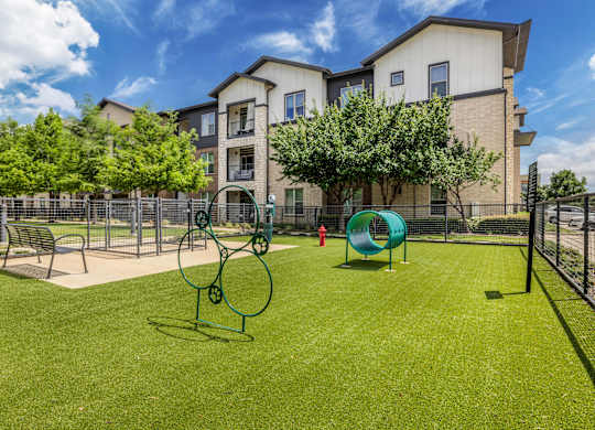 A playground with a slide, swings, and a bench in front of a building.