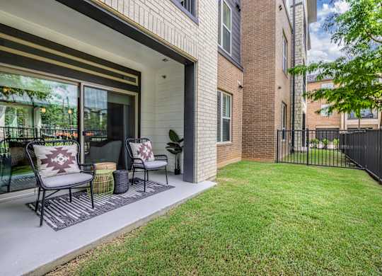 A patio with a black metal chair and a red and white pillow.
