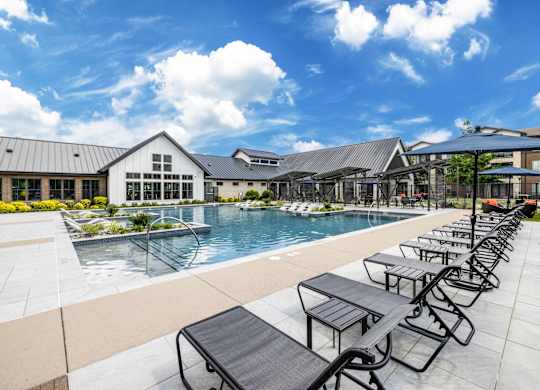 A pool area with sun loungers and a building in the background.