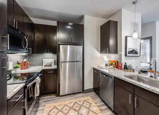 A modern kitchen with dark wood cabinets and stainless steel appliances.