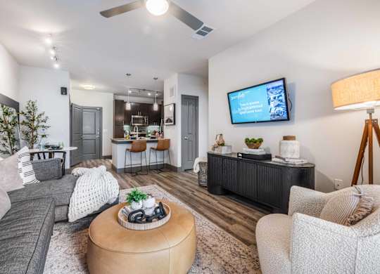 A modern living room with a grey couch, a wooden coffee table, and a flat-screen TV mounted on the wall.