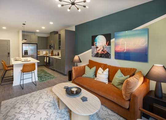 a living room with an orange couch and a kitchen with a table and chairs
