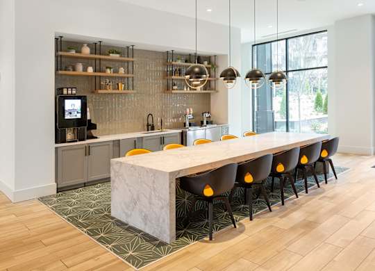 a kitchen with a marble counter top and a long table with yellow chairs