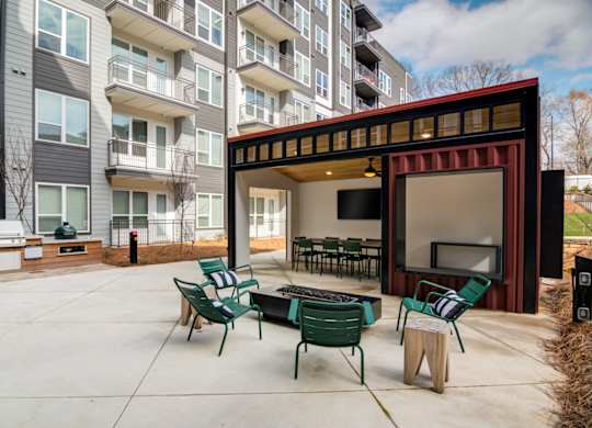 a patio with chairs and a fire pit in front of an apartment building