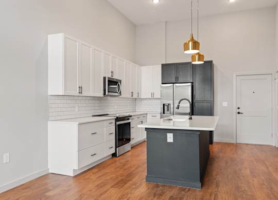 A kitchen with a black island and white cabinets.