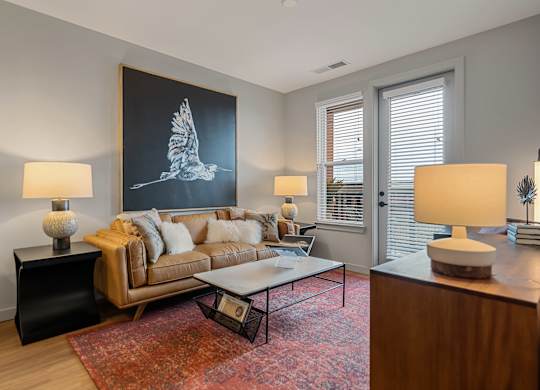 A living room with a couch, a coffee table, and a large painting of a bird.