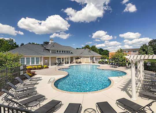 A large outdoor swimming pool surrounded by sun loungers and a covered seating area.