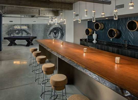 a long bar with stools in a room with a pool table