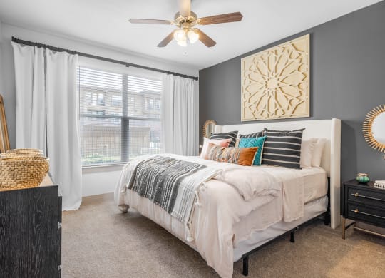 bedroom with queen size bed, large windows and ceiling fan.