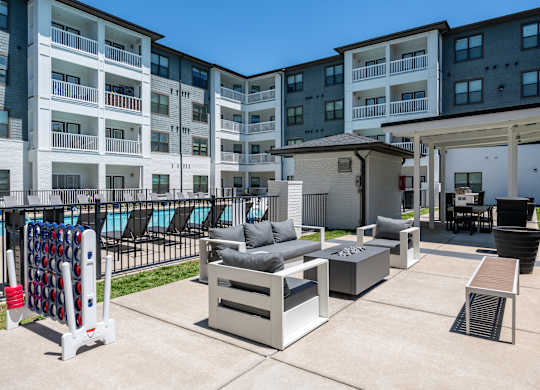A patio area with a table, chairs, and a pool in the background.