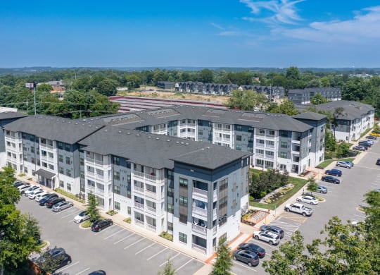 an aerial view of a large apartment complex with a parking lot and trees