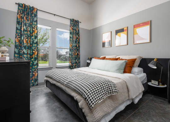 a bedroom with gray walls and a black and white bed with orange and black pillows