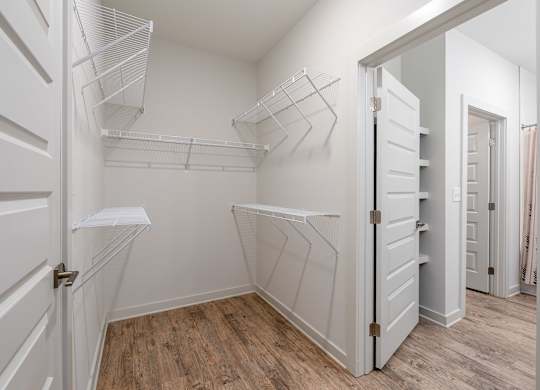 A white closet with shelves and a wooden floor.