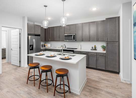 A kitchen with a white island and brown bar stools.
