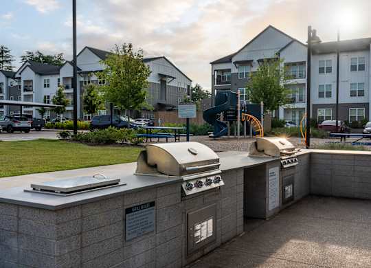 A sunny day at a residential complex with a bbq grill in the foreground.