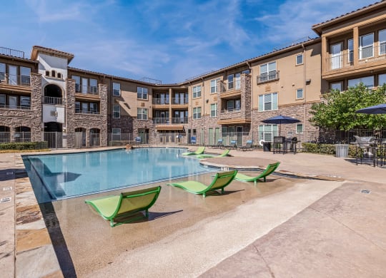 our apartments have a large swimming pool with green chairs