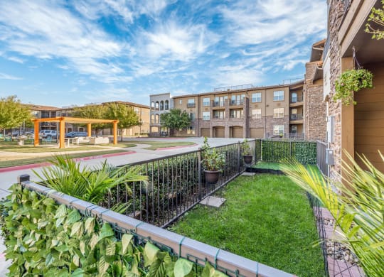 a backyard with a lawn and a fence and an apartment building