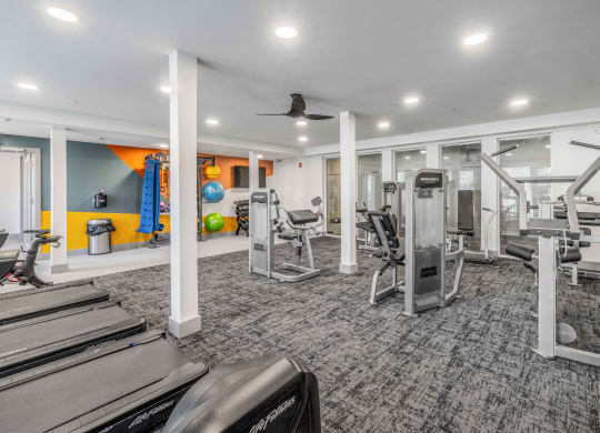 a gym with treadmills and other exercise equipment in a building with white ceilings