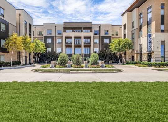 an exterior view of an apartment building with grass and trees