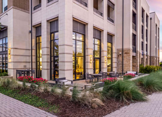 a building with large windows and a patio with tables and chairs