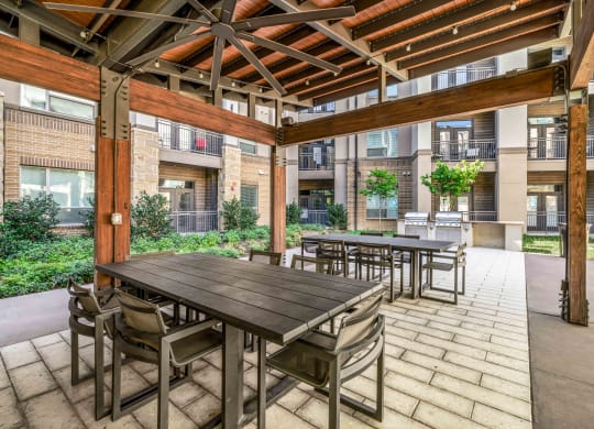 a patio with wooden tables and chairs and an apartment building in the background