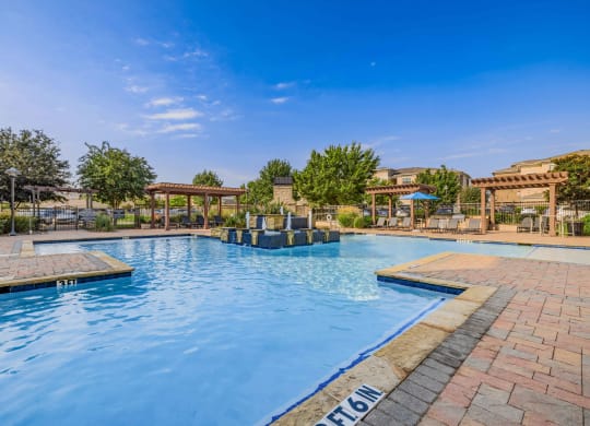 a swimming pool with trees and a blue sky above it
