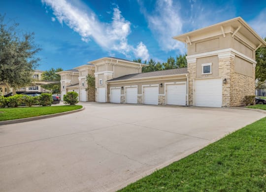 a driveway leading to a building with white garage doors