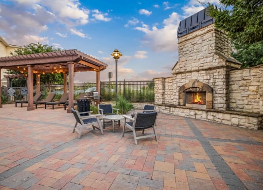 a patio with a stone fireplace and a table with chairs