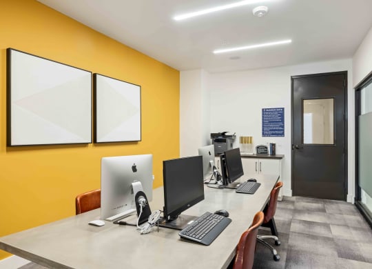our office is equipped with a large desk with computers and a yellow wall