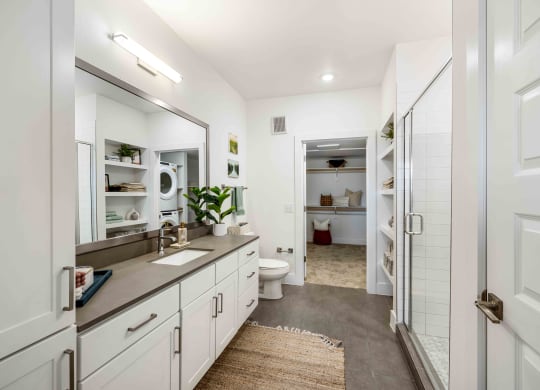 a bathroom with white cabinets and a shower and a sink
