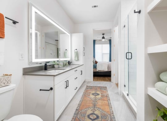 a white bathroom with a large mirror and a rug