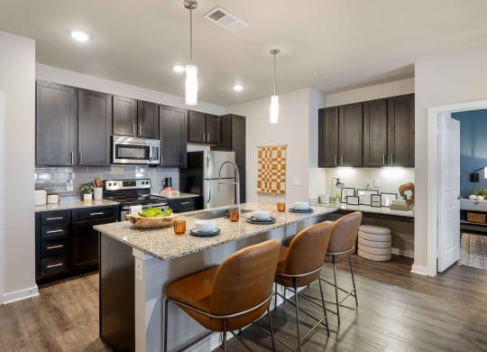 a kitchen with a large island with chairs and a counter top
