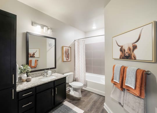 a bathroom with a shower and a toilet and a painting of a bull