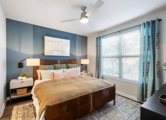 a bedroom with blue walls and a large window and a bed