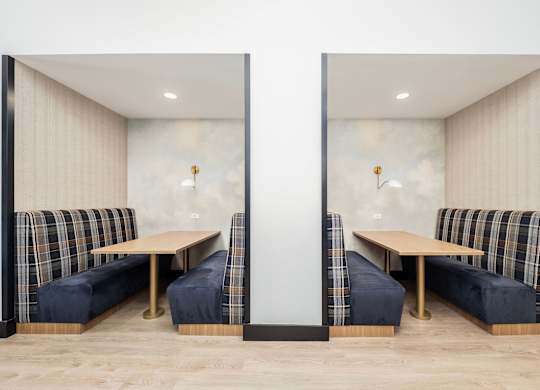 Two identical booths with plaid cushions and wooden tables.