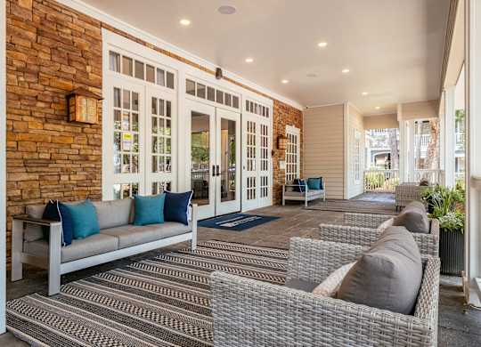 A patio with a couch, chairs, and a brick wall.
