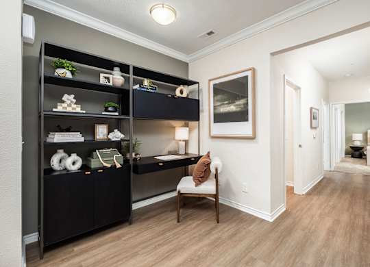 A hallway with a chair and a shelf with decorations.