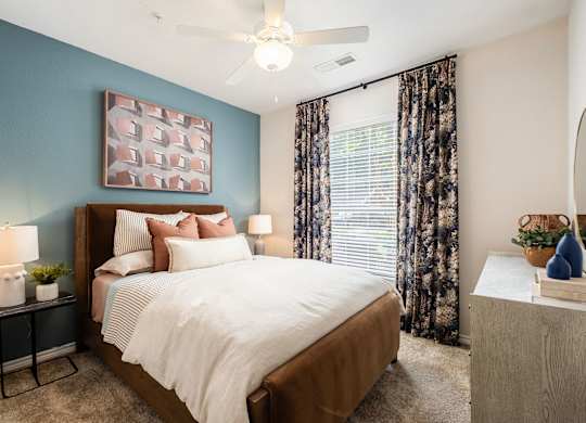A bedroom with a large bed and a ceiling fan.