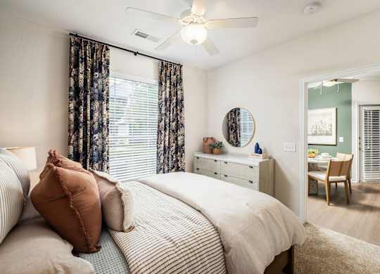 A bedroom with a bed, dresser, mirror, and chair.