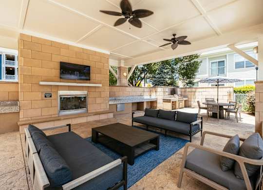 A patio with a black table and grey couches.