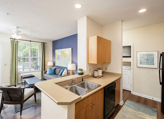 A kitchen with a black refrigerator and a dining table with chairs.