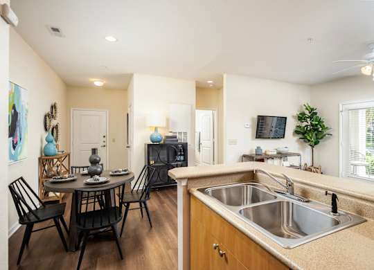 A kitchen with a table and chairs in the foreground and a television in the background.
