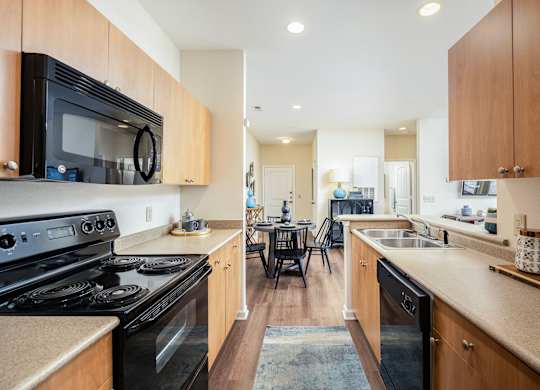 A kitchen with a black stove top oven and wooden cabinets.