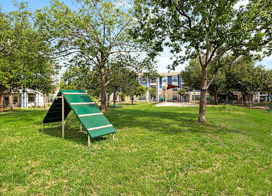 A playground with a green slide and a green bench.