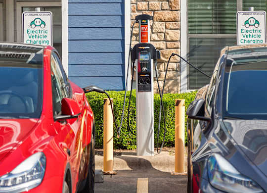 Two cars are parked at an electric vehicle charging station.