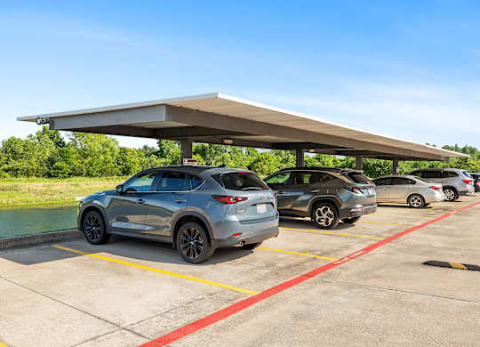 A parking lot with cars under a canopy.